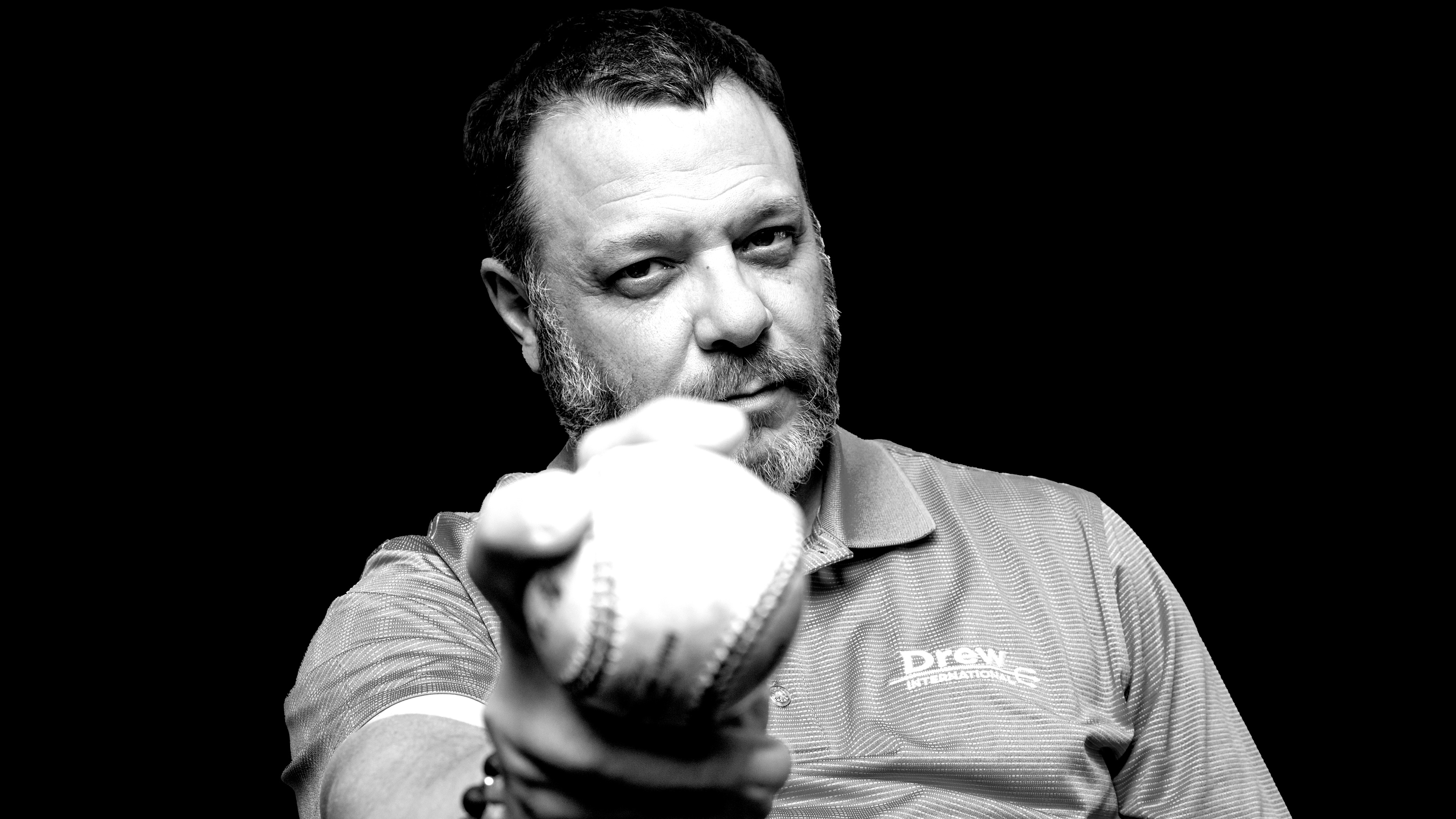 Black and white photo of Frank Monteiro of Waterbury CT holding a baseball, wearing a Drew International shirt