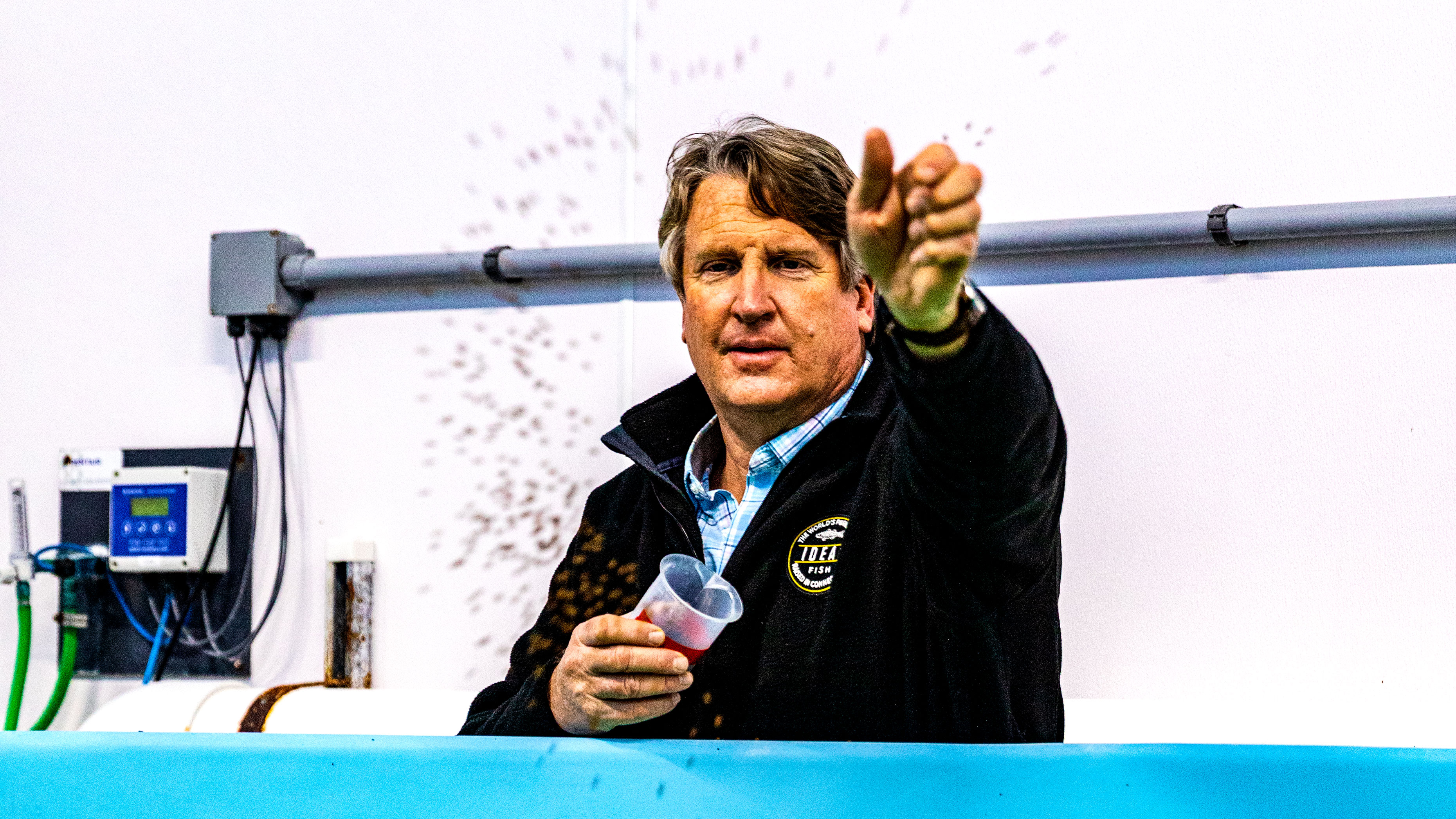 Eric Pedersen throwing fish food into tank at Ideal Fish in Waterbury, CT