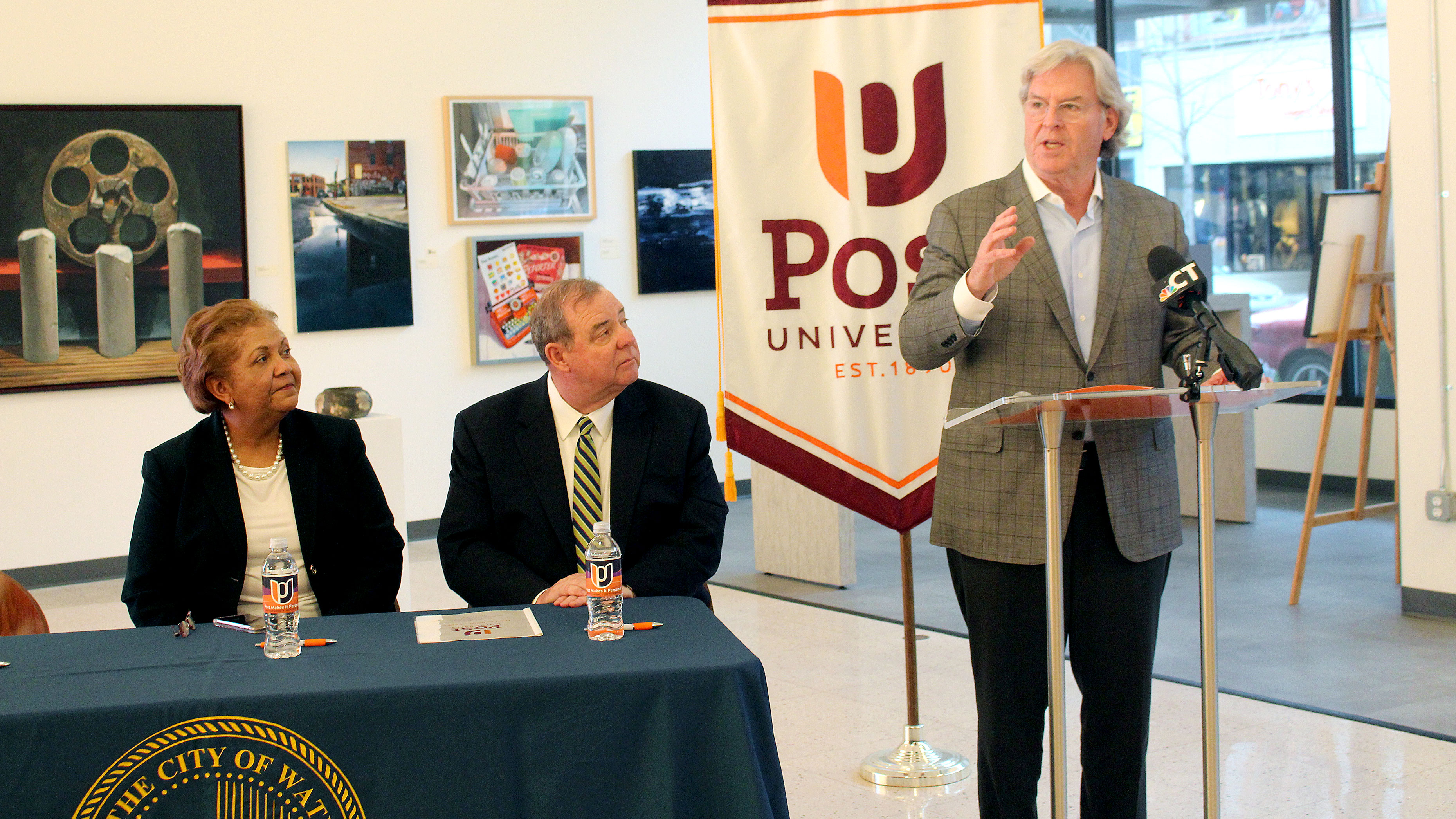 John Hopkins giving a speech at Post University in Waterbury CT as Dr. Verna Ruffin and Major Neil O'Leary look on