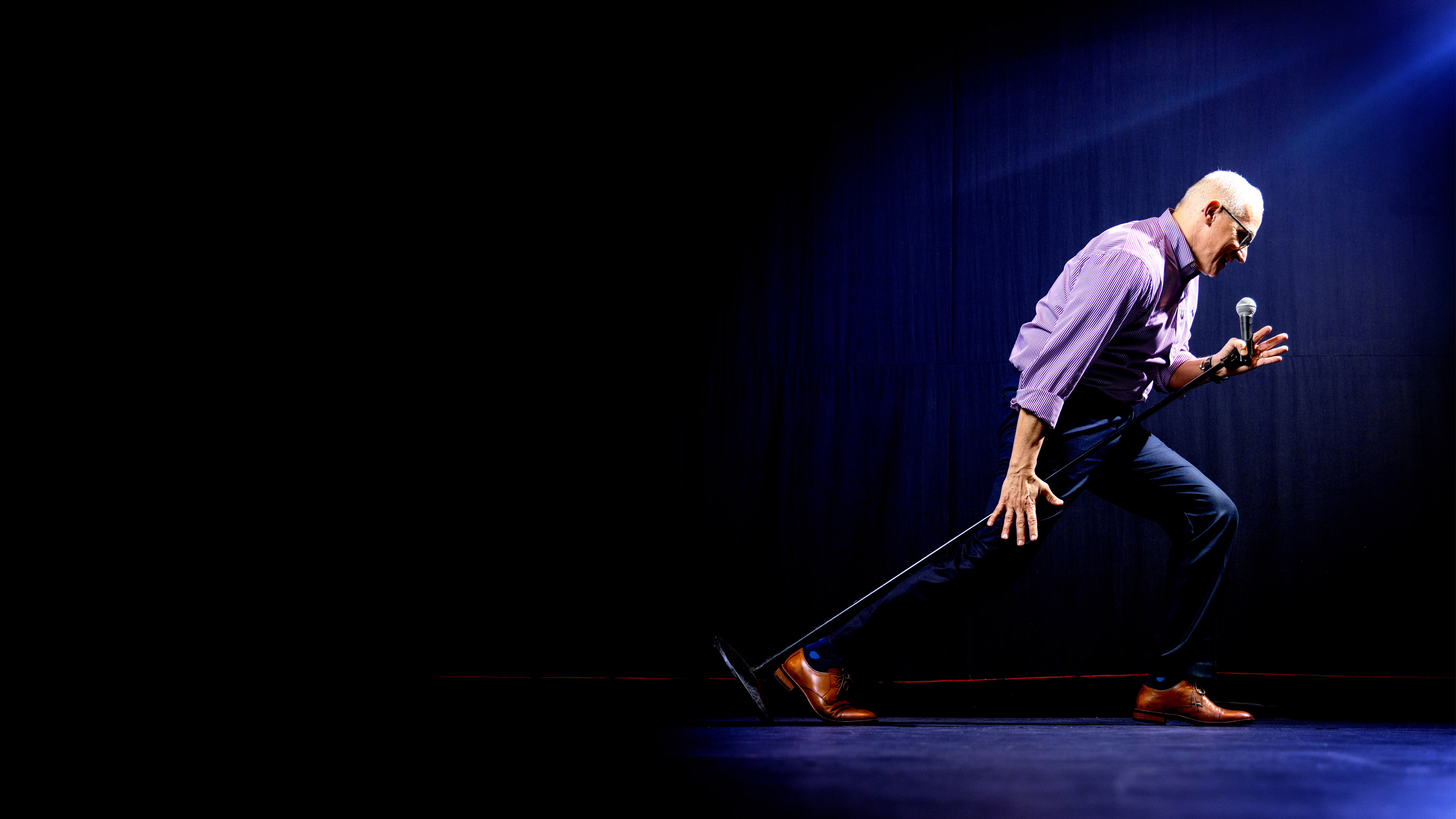 Palace Theater CEO Frank Tavera leaning forward into a microphone in a mock performance on stage