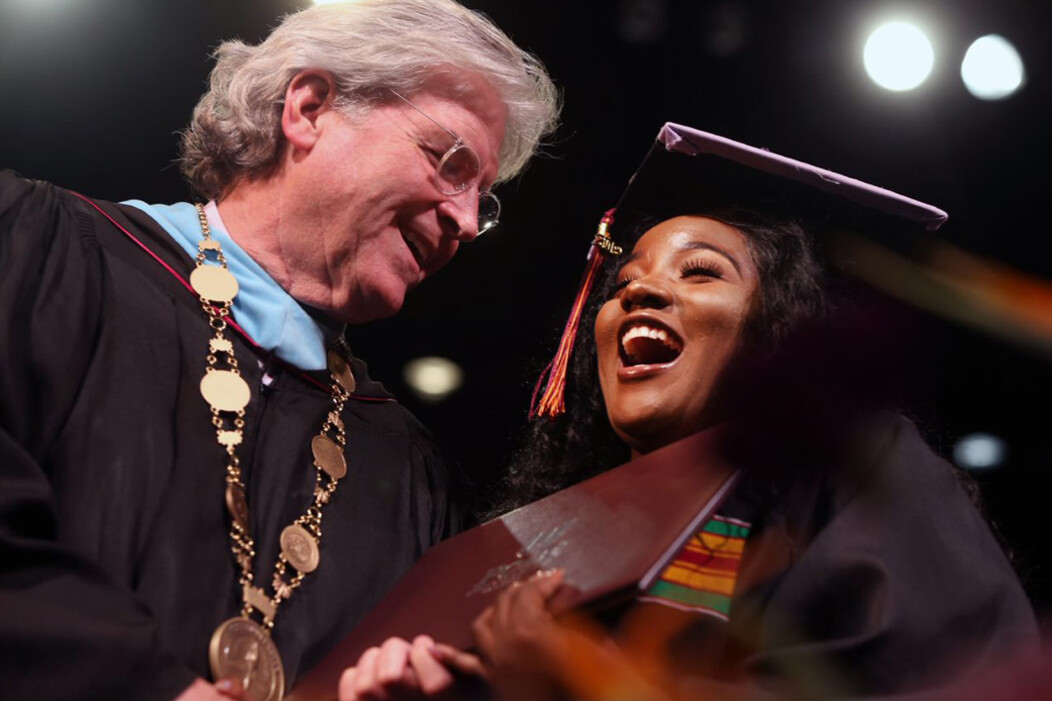 John Hopkins smiling with a Post University graduate holding a diploma