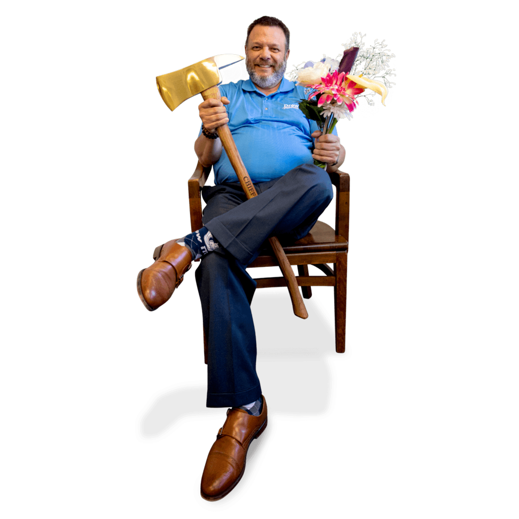 Frank Monteiro of Waterbury CT sits in chair smiling, holding a brass axe and bouquet of flowers