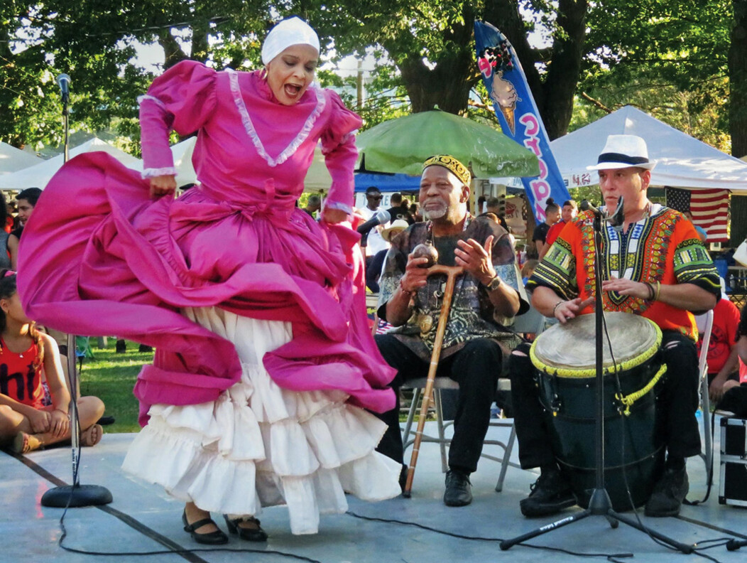 A woman dancing on stage in a traditional dress at The Gathering event in Waterbury, Connecticut.