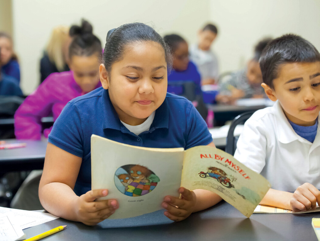 A young student reading a picture book at the Waterbury PAL after school program