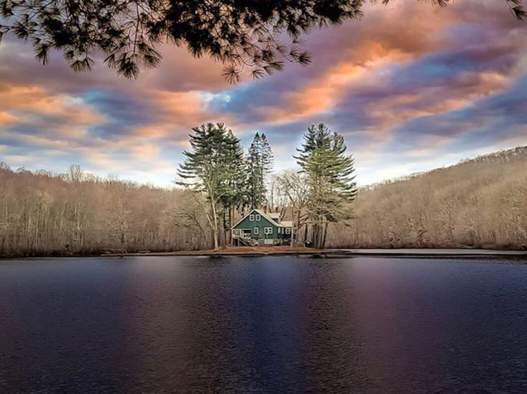 A house and trees on a small island at Tobys Pond in Beacon Falls CT