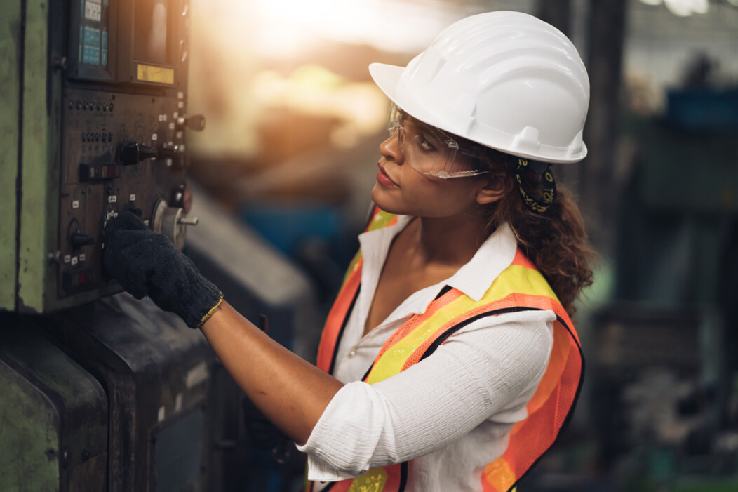 Female worker wearing a white hardhat and orange safety vest