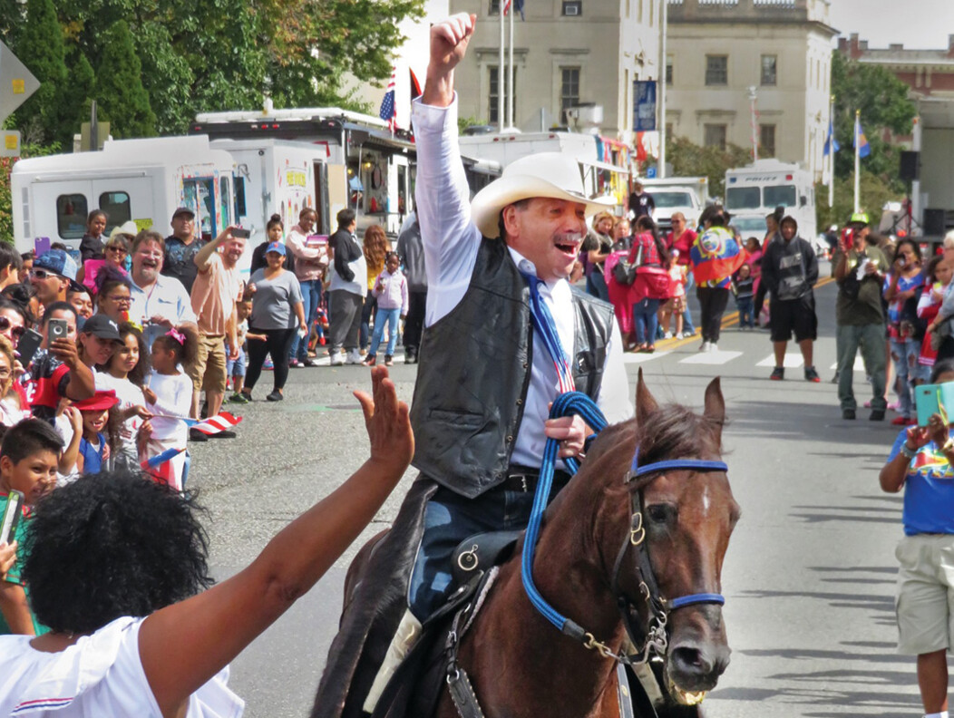 A man on a horse with his fist in the air, riding through Waterbury, Connecticut.