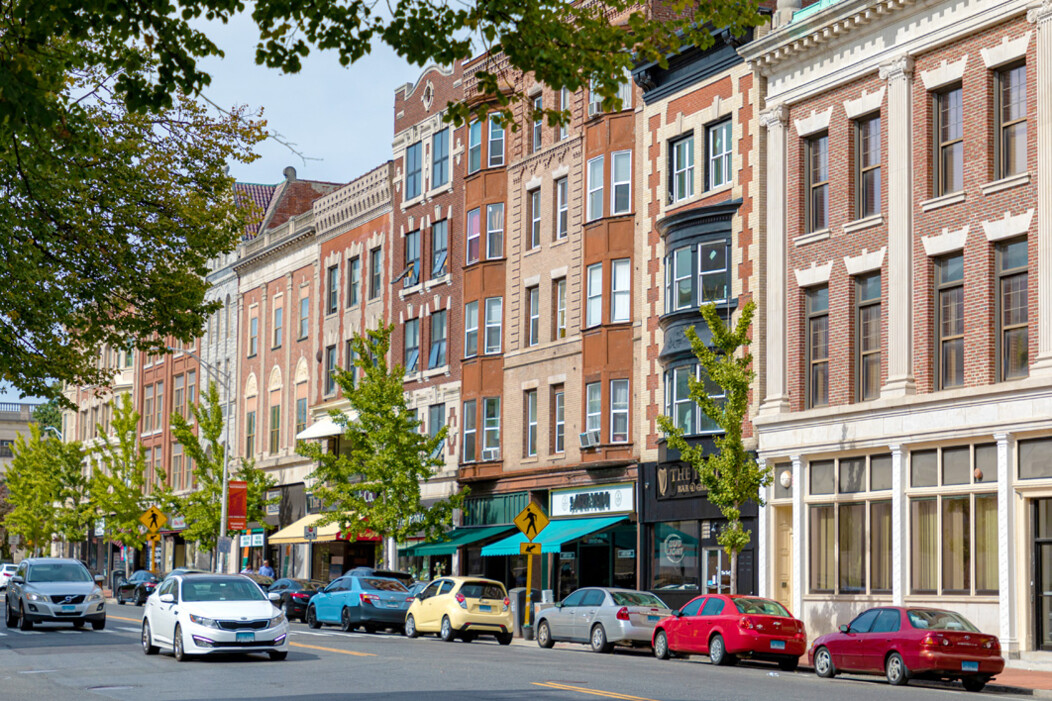 Sidewalk view of traffic and businesses on Grand Street in downtown Waterbury, CT